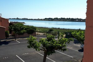 A parking lot with a view of a calm body of water and distant buildings. - Holiday home in Gruissan with swimming pool (Gruissan)