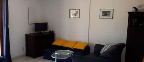 A living room with a sofa, a small round table, a TV, and a cabinet.
