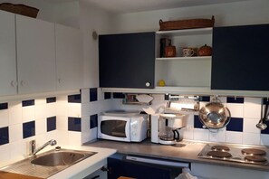 A kitchen with white cabinets, a microwave, a coffee maker, and a stove. - Holiday home in Gruissan with swimming pool (Gruissan)