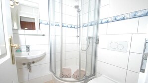 Un bagno con doccia vetro, lavandino e water.