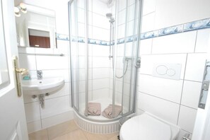 A bathroom with a glass-enclosed shower, a sink, and a toilet. - Holiday apartment in Sylt with 1 bedroom (Wenningstedt)