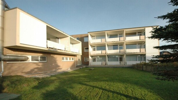 Un edificio residenziale moderno a più piani con balconi e un prato curato.