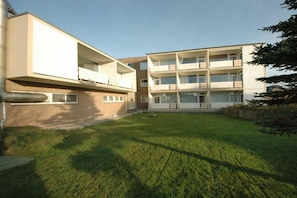 A modern multi-story residential building with balconies and a well-maintained lawn. - Holiday apartment in Sylt with 1 bedroom (Wenningstedt)