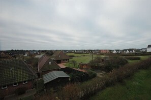 A residential area with houses, a grassy field, and a cloudy sky. - Holiday apartment in Sylt with 1 bedroom (Wenningstedt)