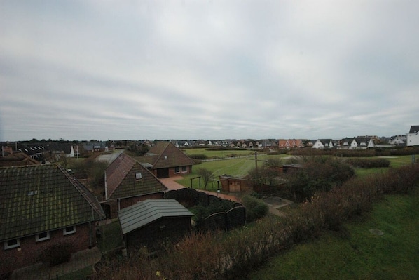 A residential area with houses, a grassy field, and a cloudy sky. - Holiday apartment in Sylt with 1 bedroom (Wenningstedt)