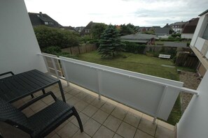 A balcony with a view of a residential area, a small table, and a chair. - Holiday apartment in Sylt with 1 bedroom (Wenningstedt)