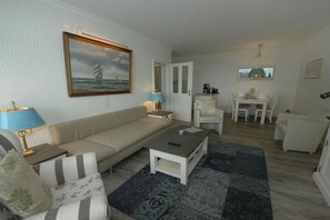A living room with a sofa, armchairs, a coffee table, and a painting on the wall. - Holiday apartment in Sylt with 1 bedroom (Wenningstedt)