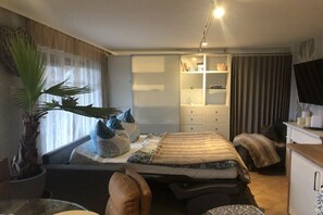Un dormitorio con cama, escritorio, silla, armario y una planta en maceta.