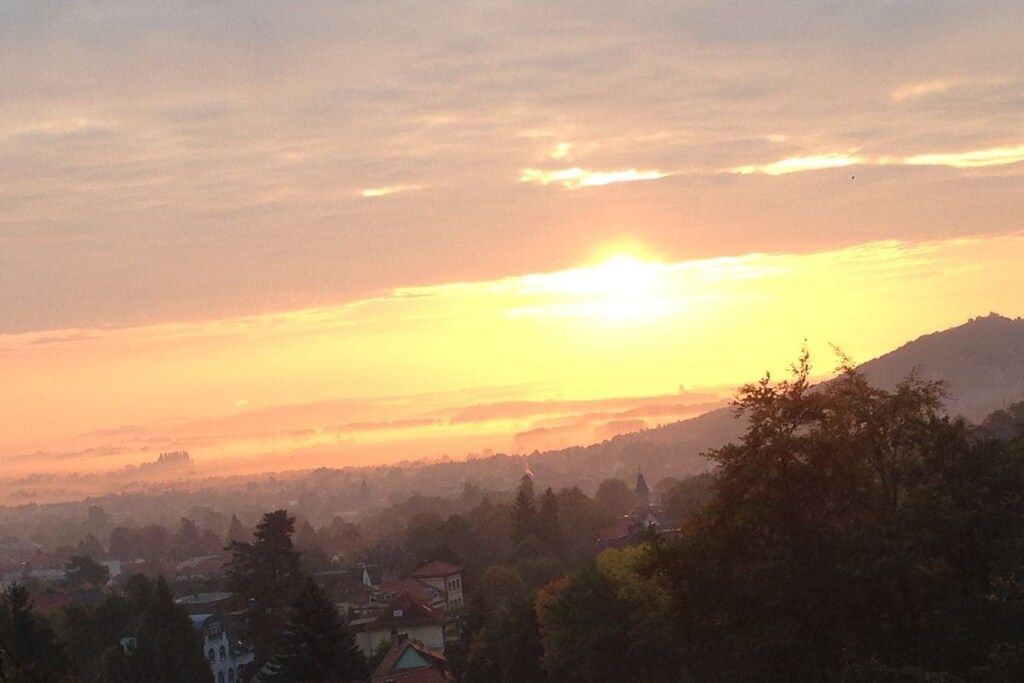 A sunset over a town with buildings and hills in the background.