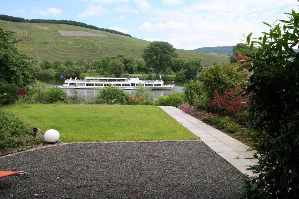 Une rivière avec un bateau, une zone herbeuse et un sentier.