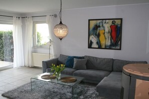 A modern living room with a grey sofa, a glass coffee table, and a hanging light fixture. - "Abundance" on the banks of the Moselle (Bernkastel-Kues\/Andel)