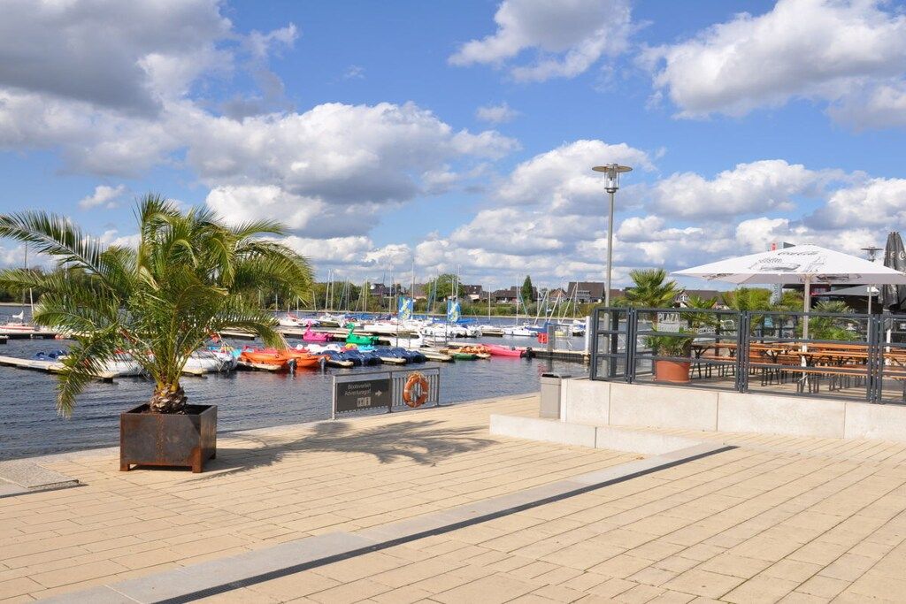 Un puerto deportivo con barcos amarrados, una palmera y un café con terraza.