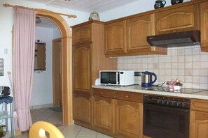 A kitchen with wooden cabinets, a microwave, a coffee maker, and a dishwasher. - Holiday apartment with 1 bedroom (Impflingen)