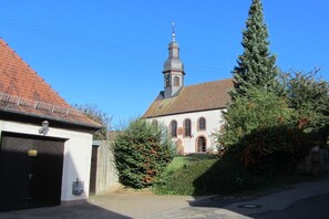 A building with a red-tiled roof, a small bell tower, and a garage. - Holiday apartment with 1 bedroom (Impflingen)