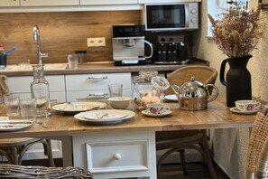 A kitchen with a wooden countertop, a coffee maker, a kettle, and various dishes. - Holiday cottage "Jantje" (Bunde)