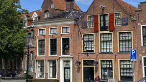 A traditional European building with a brick facade, multiple windows, and a blue parking sign. - Holiday cottage "Jantje" (Bunde)