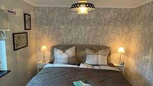 A bedroom with a bed, two bedside tables, a lamp, and a wall-mounted light fixture. - Holiday cottage "Jantje" (Bunde)