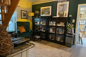 A cozy living room with a green armchair, a bookshelf, and a globe on a table. - Holiday cottage "Jantje" (Bunde)