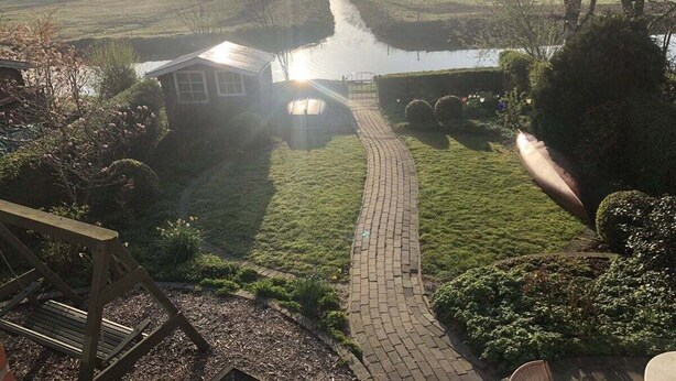 A pathway leading to a house with a pond in the background. - Holiday cottage "Jantje" (Bunde)