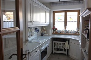 A kitchen with white cabinetry, a window with curtains, and a countertop with various kitchen items. - Holiday apartment with 1 bedroom (Aschau\/Chiemgau)