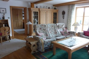 A cozy living room with a floral sofa, wooden coffee table, and a cabinet with glass doors. - Holiday apartment with 1 bedroom (Aschau\/Chiemgau)