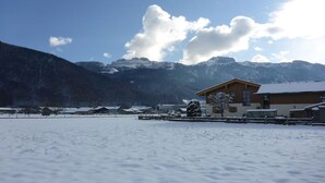 Un paysage enneigé avec un bâtiment en bois et des montagnes en arrière-plan.