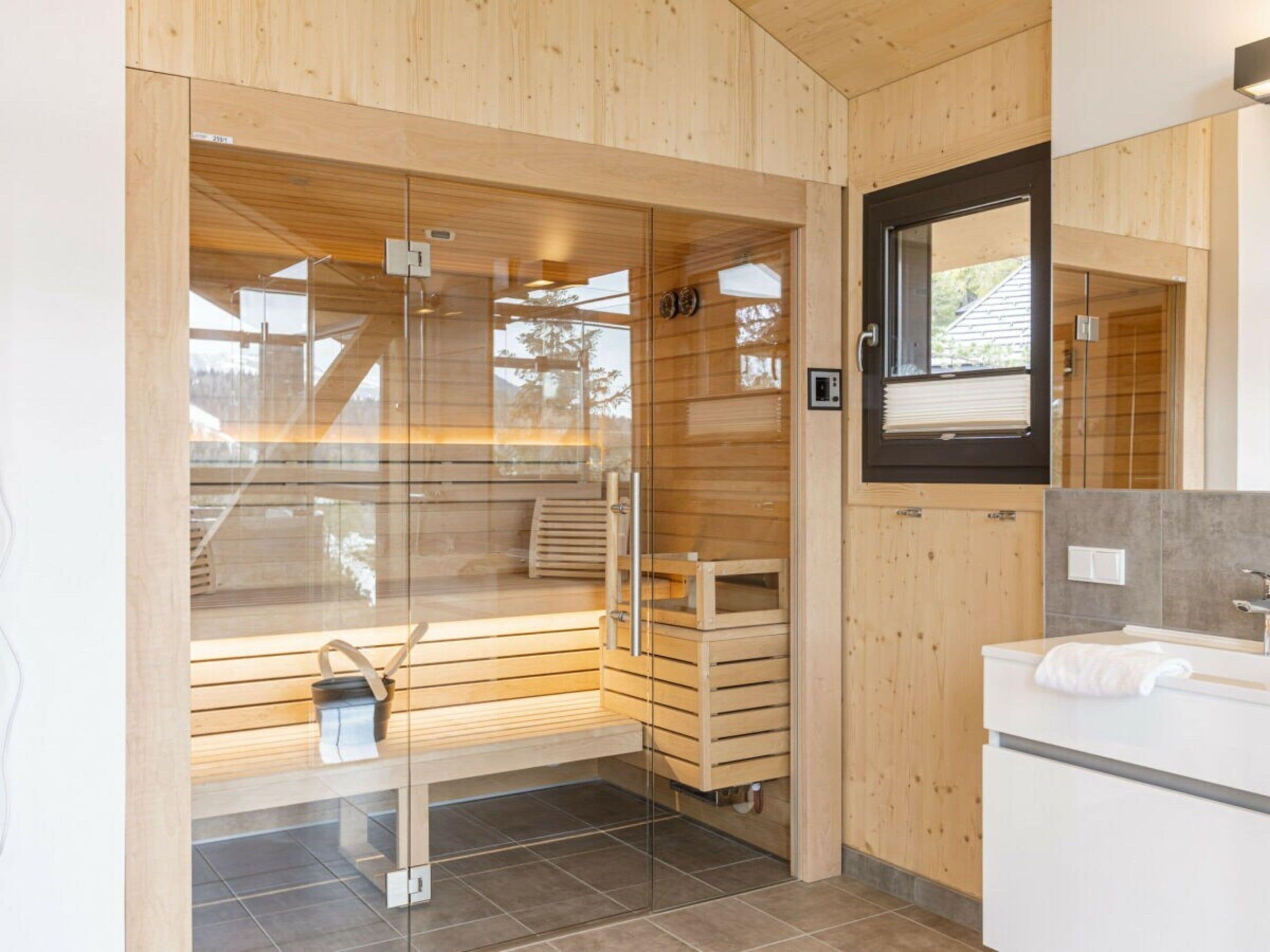 A modern bathroom with wooden paneling, a glass shower enclosure, and a white sink.