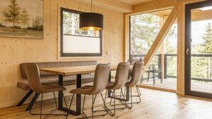 A wooden interior with a dining table and chairs, a hanging light fixture, and a window with blinds. - Superior Chalet #16 With Sauna & Hot Tub (Stadl-Predlitz)