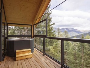 A wooden deck with a hot tub and a view of a forested mountain range. - Superior Chalet #16 With Sauna & Hot Tub (Stadl-Predlitz)