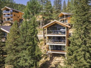 A modern wooden cabin with multiple balconies, surrounded by dense forest. - Superior Chalet #16 With Sauna & Hot Tub (Stadl-Predlitz)