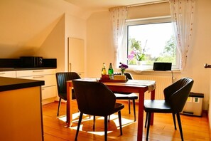 Eine Küche mit Esstisch, Stühlen und einem Fenster mit Vorhängen.