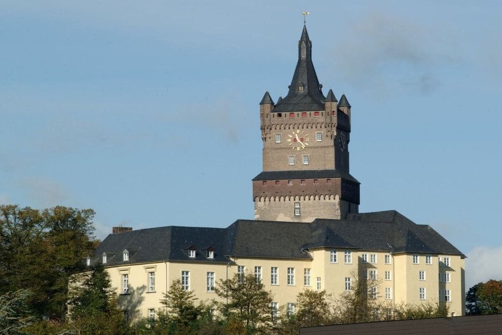 Un edificio grande con una torre de reloj destacada y numerosas ventanas.