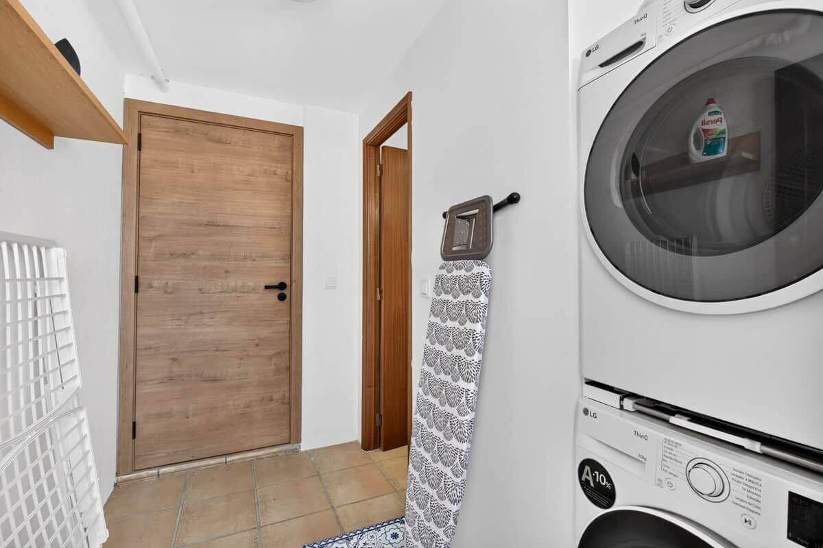 A laundry room with a washing machine, a wooden door, and a patterned towel hanging on a hook.