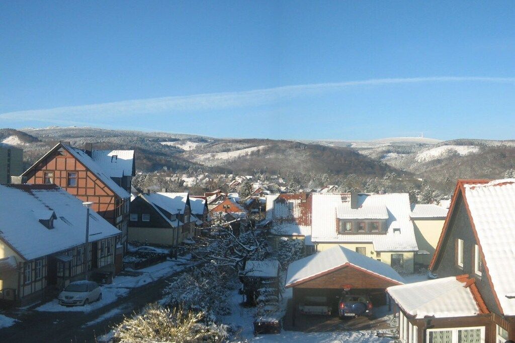 A residential area with houses covered in snow, surrounded by hills.