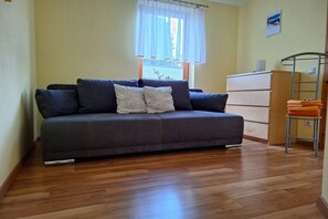 A room with a sofa, a wooden dresser, and a window with curtains. - Holiday apartment with 2 bedrooms (Wernigerode)