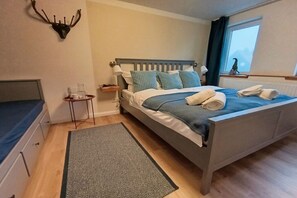 A bedroom with a bed, bedside table, lamp, and a wall-mounted deer head decoration. - Bergstadthaus Sankt Andreasberg (St. Andreasberg)