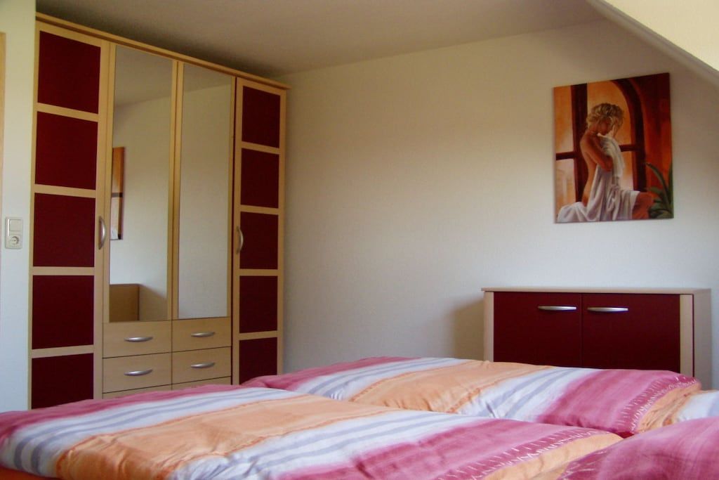Ein Schlafzimmer mit einem Bett, einem Kleiderschrank und einem Bild an der Wand.