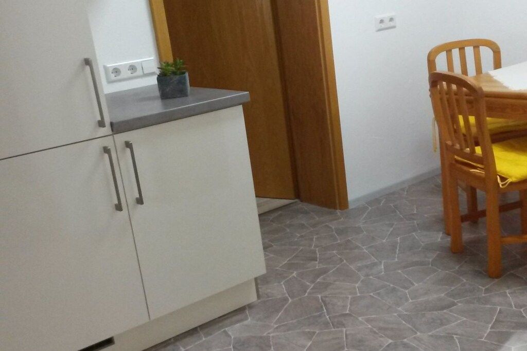 Una cocina con armarios blancos, una encimera y una silla de madera con cojín amarillo.
