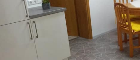 Una cocina con armarios blancos, una encimera y una silla de madera con cojín amarillo.