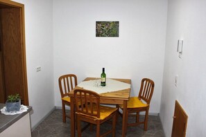 Una piccola zona pranzo con tavolo in legno e quattro sedie, una bottiglia di vino e una piccola pianta sul bancone.