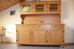 Un meuble en bois doté de portes en verre et d’une poignée décorative.