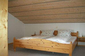 Ein Einzelbett aus Holz mit Kopfteil, einem Nachttisch und einem Beistelltisch mit Lampe.