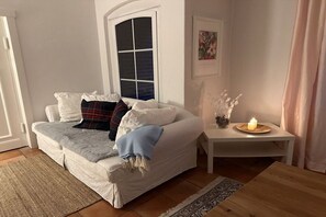 A cozy living room with a sofa, a small table with a candle, and a window with a view. - Sophienhof "Casimir" (Neuenkirchen)