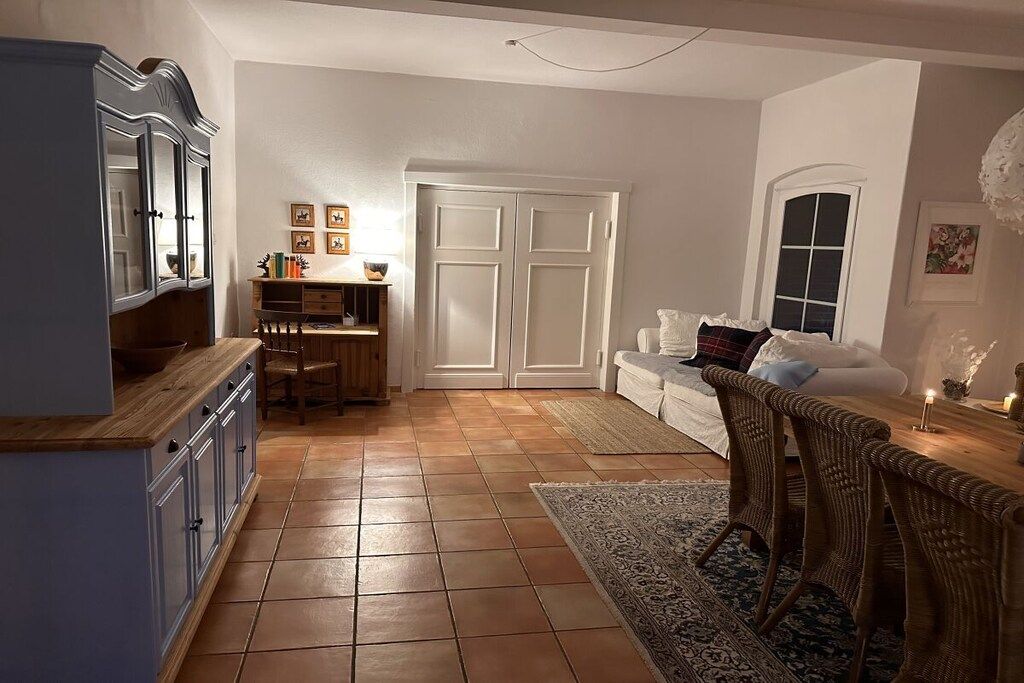 A room with a dining area, a sofa, and a cabinet.