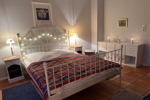 Ein Schlafzimmer mit einem Bett, Nachttischen, einer Kommode und einem gerahmten Bild an der Wand.
