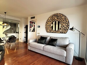 A modern living room with a grey sofa, black cushions, a round wall decoration, and a floor lamp. - Beautiful Marilyn, 4th Floor, Marina Botafoch, Ibiza (Eivissa)