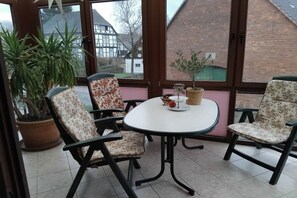 Ein Essbereich mit einem runden Tisch und vier Stühlen, umgeben von großen Fenstern mit Blick auf Häuser.