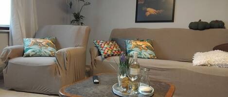 A living room with a sofa, armchair, and a coffee table with a tray of items.