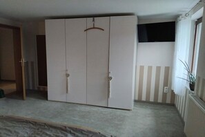 Une chambre dotée d’une grande armoire, d’un téléviseur fixé au mur et d’un radiateur.