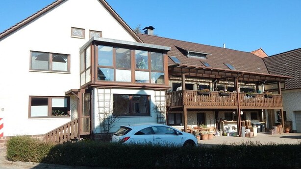 A two-story house with a car parked in front, a balcony, and a covered porch area. - ||------------------------House-in-the-curve------------------|| (Halle-Dohnsen)